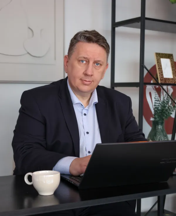 Grzegorz Bora przy biurku z laptopem i filiżanką